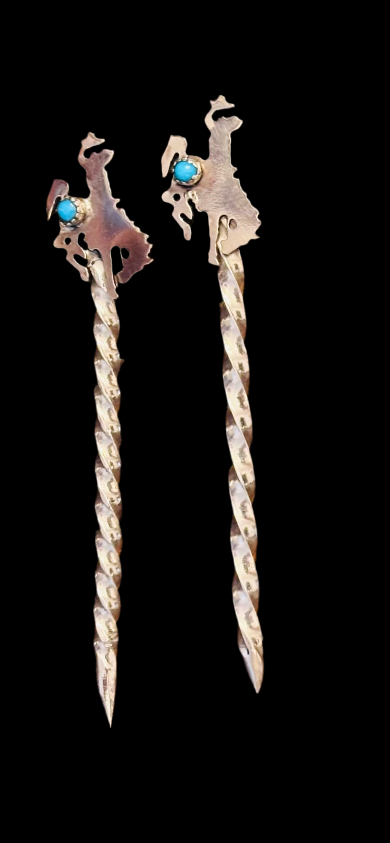 Two decorative hair pins with intricate designs and turquoise stones on a black background