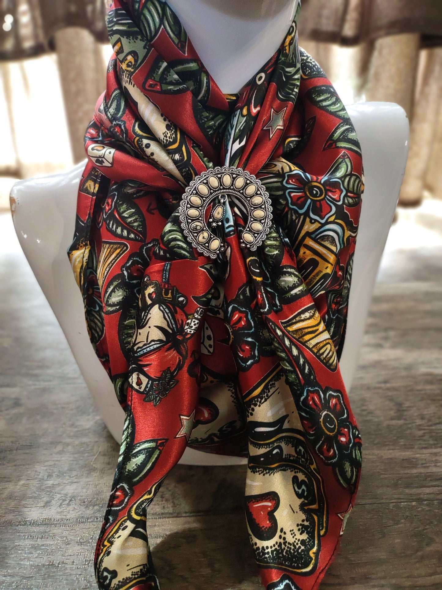 Colorful patterned scarf with a decorative brooch on a mannequin against a neutral background