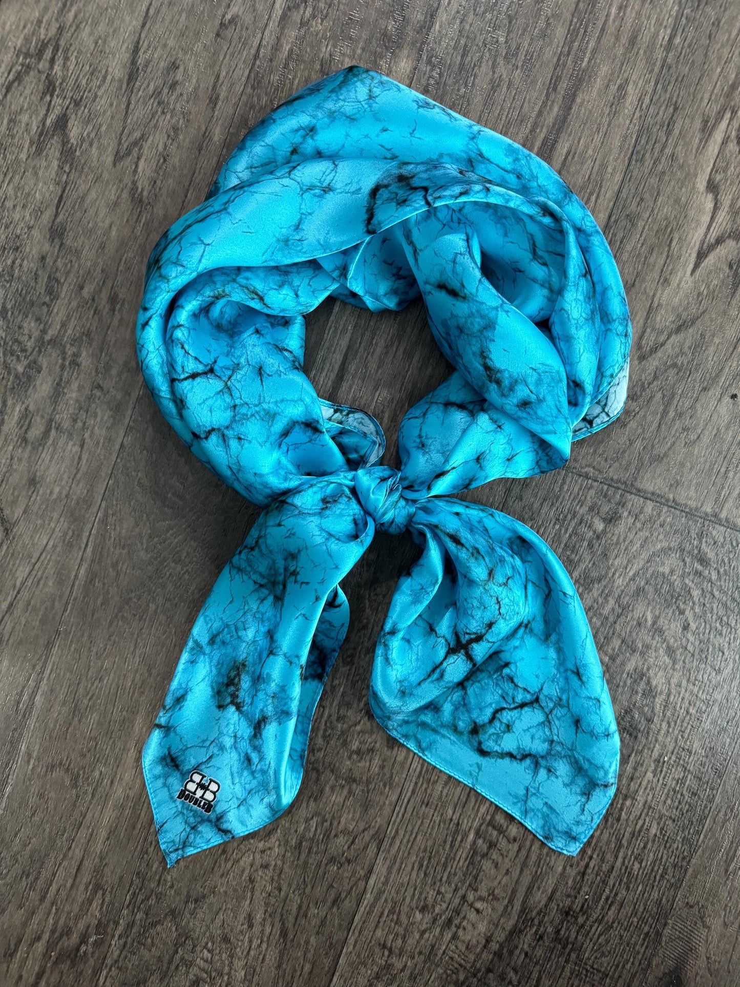 Turquoise scarf with black patterns on a wooden surface