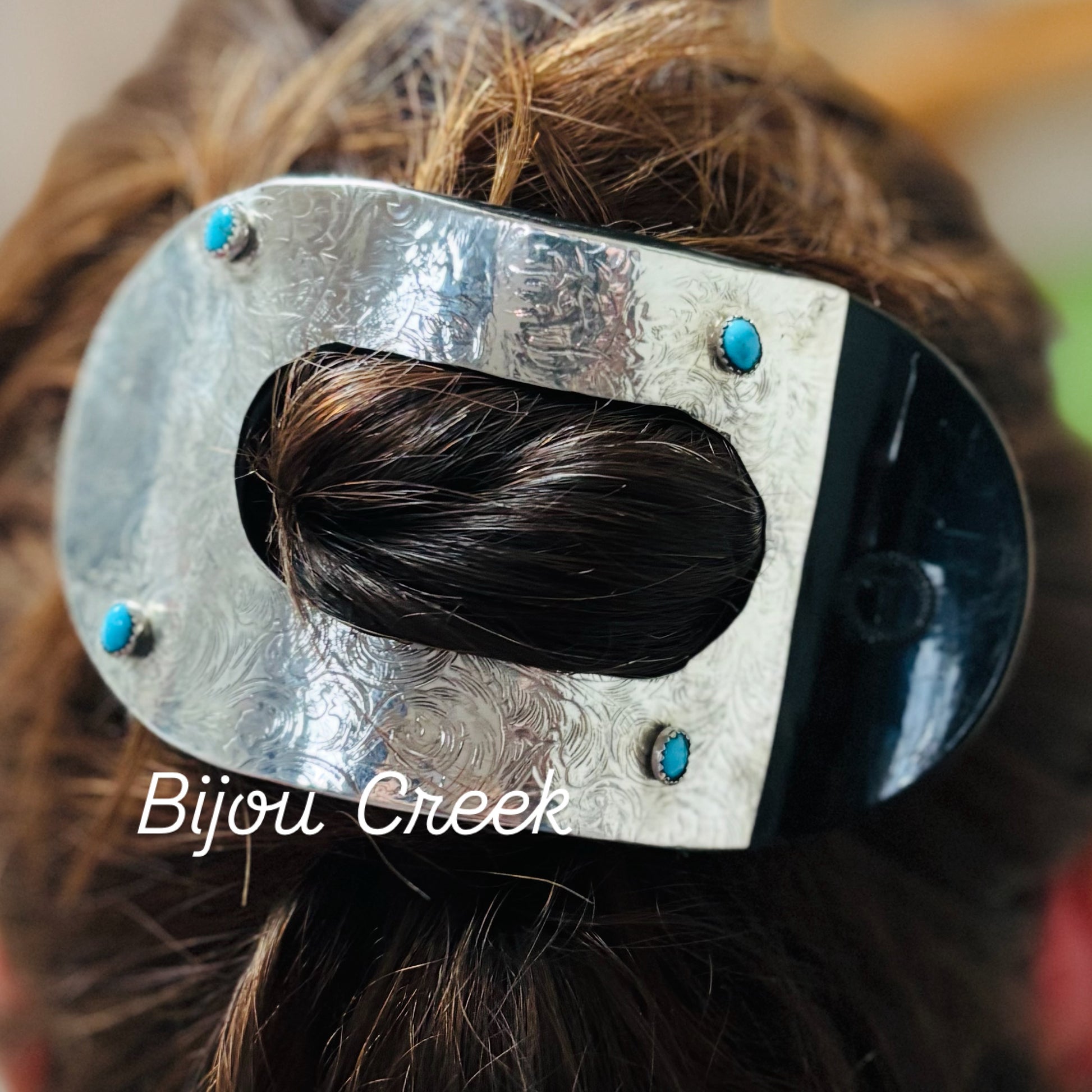 Metal hair clip with turquoise stones on a person's hair, branded 'Bijou Creek'.