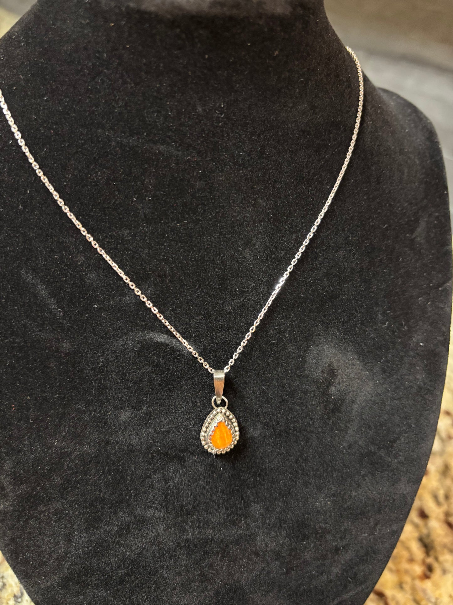Necklace with an orange heart pendant on a black surface