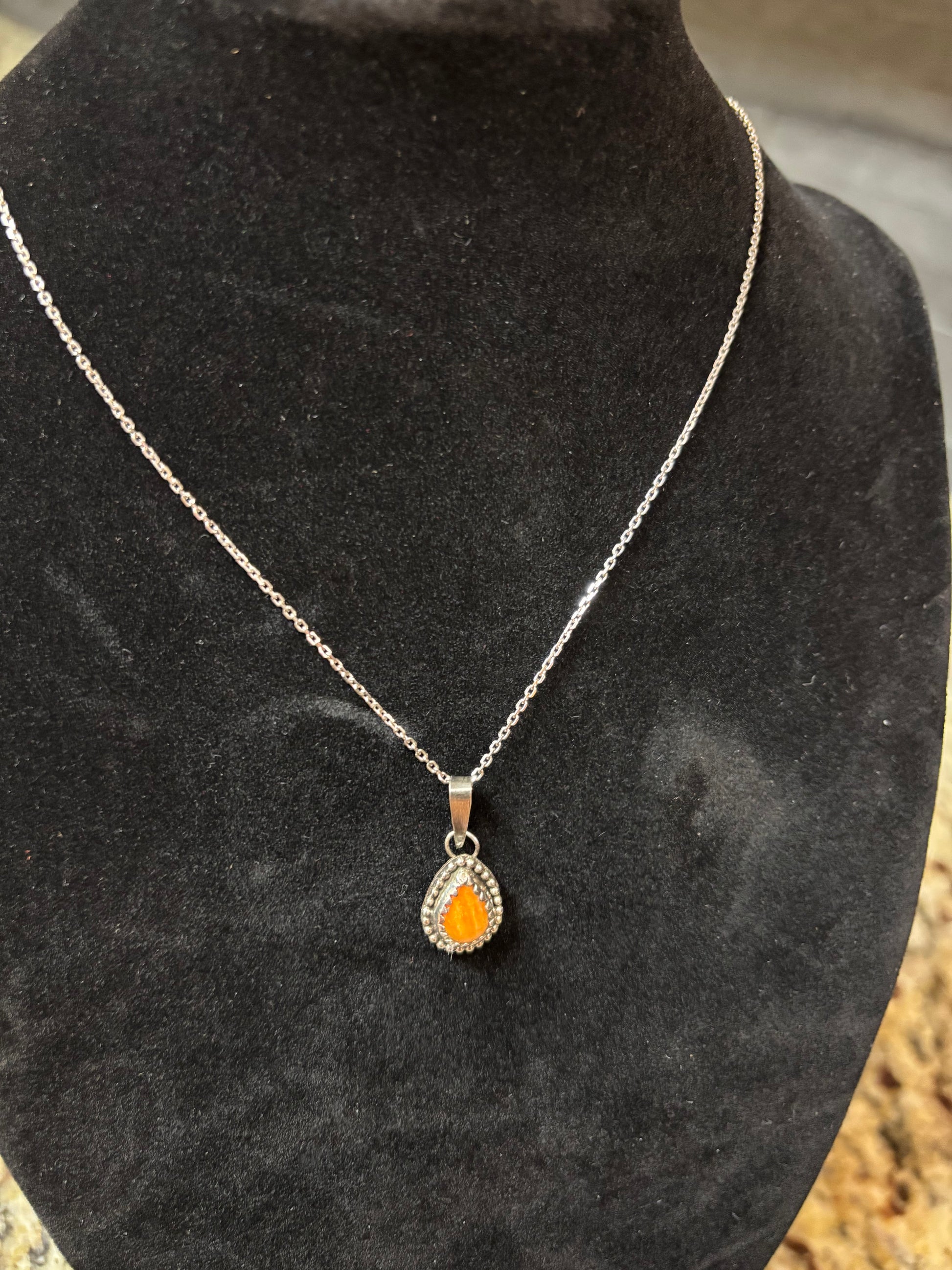 Necklace with an orange heart pendant on a black surface