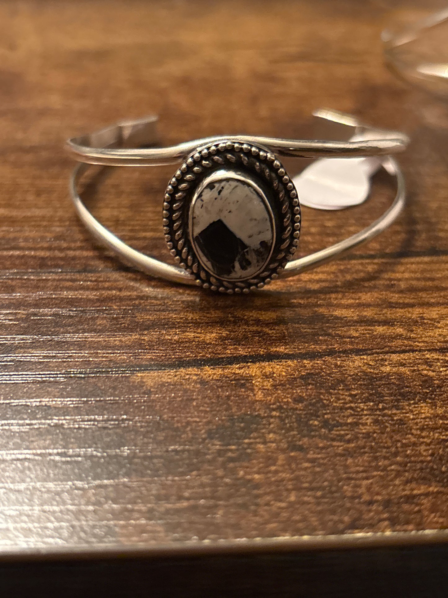Silver ring with a dark stone on a wooden surface