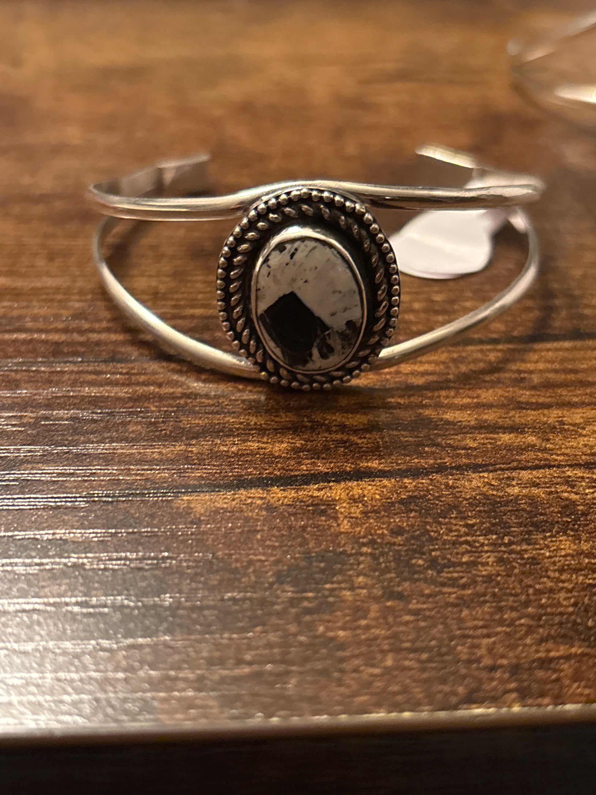 Silver ring with a dark stone on a wooden surface