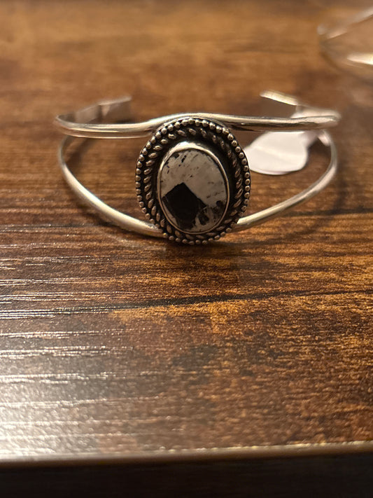 Silver ring with a dark stone on a wooden surface