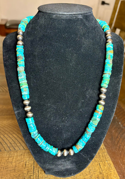 Turquoise and silver beaded necklace on a black mannequin bust.
