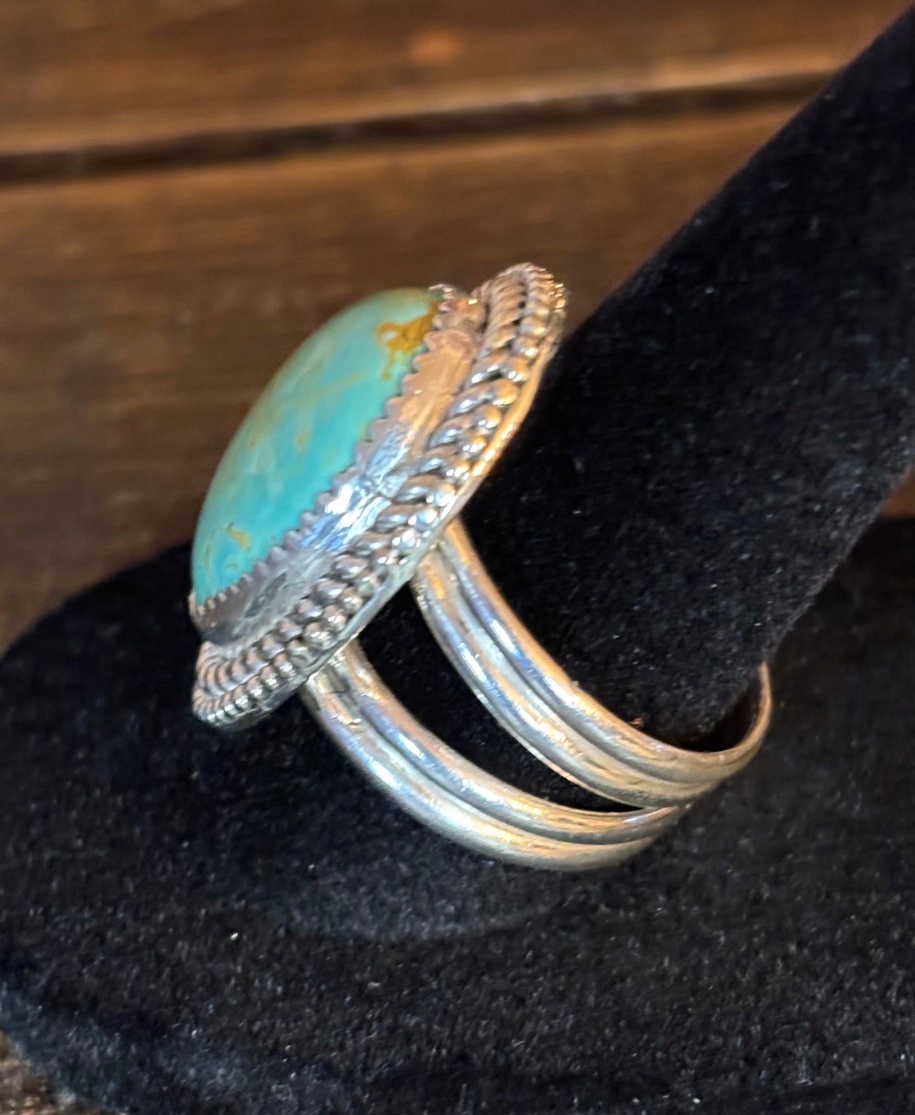 Silver ring with turquoise stone on a black velvet surface