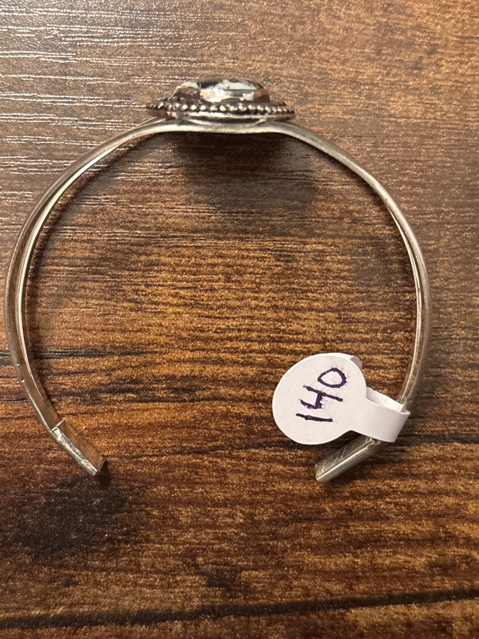 Silver bracelet with a tag labeled '041' on a wooden surface