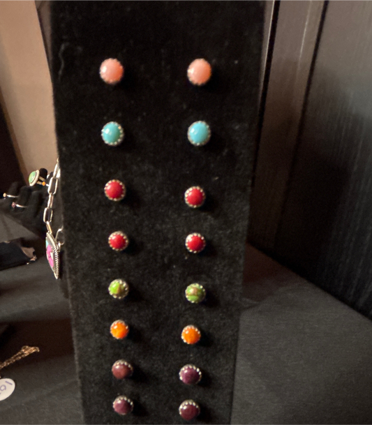 Collection of colorful earrings on a black stand.