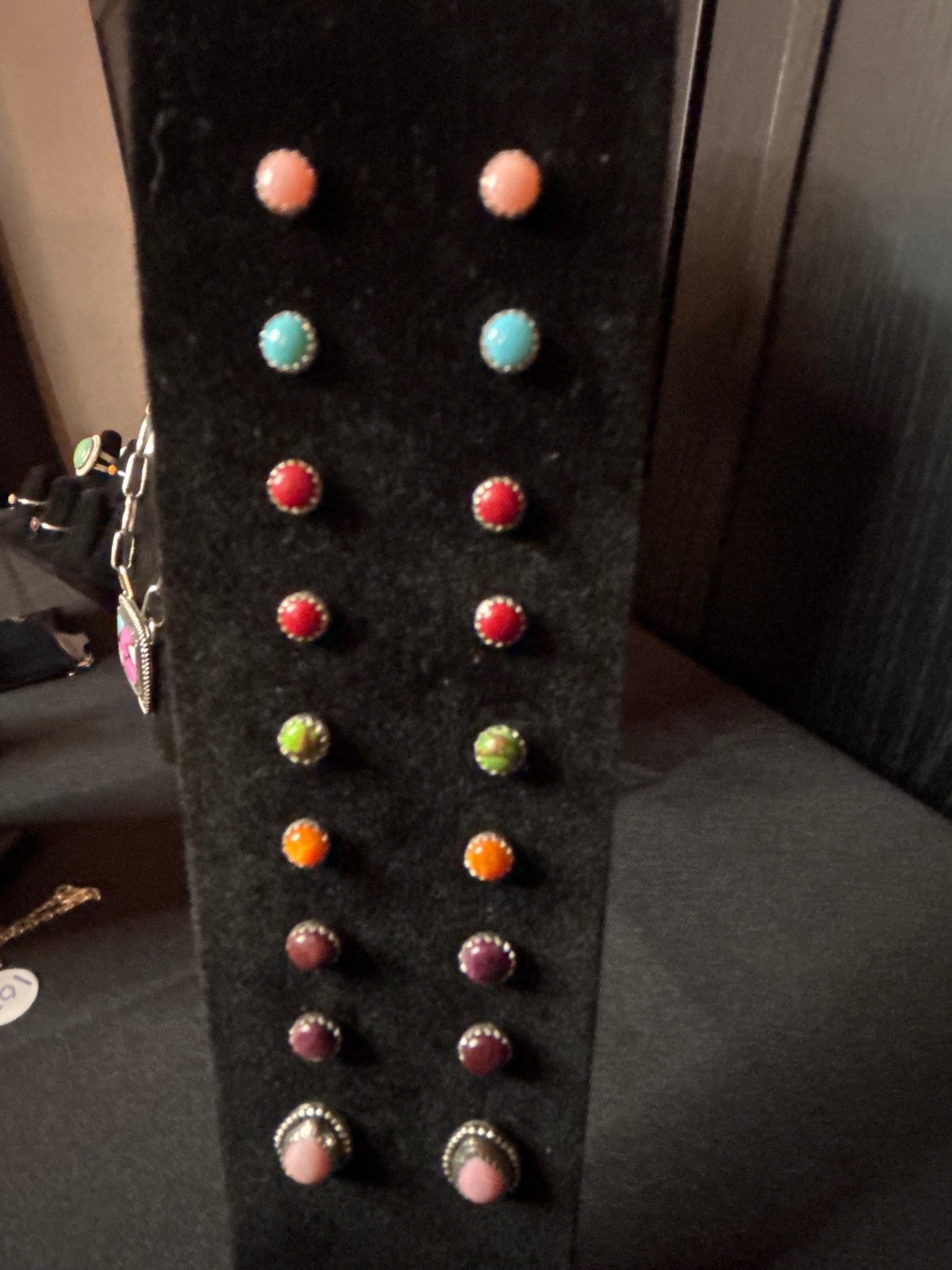 Collection of colorful earrings on a black earring stand.