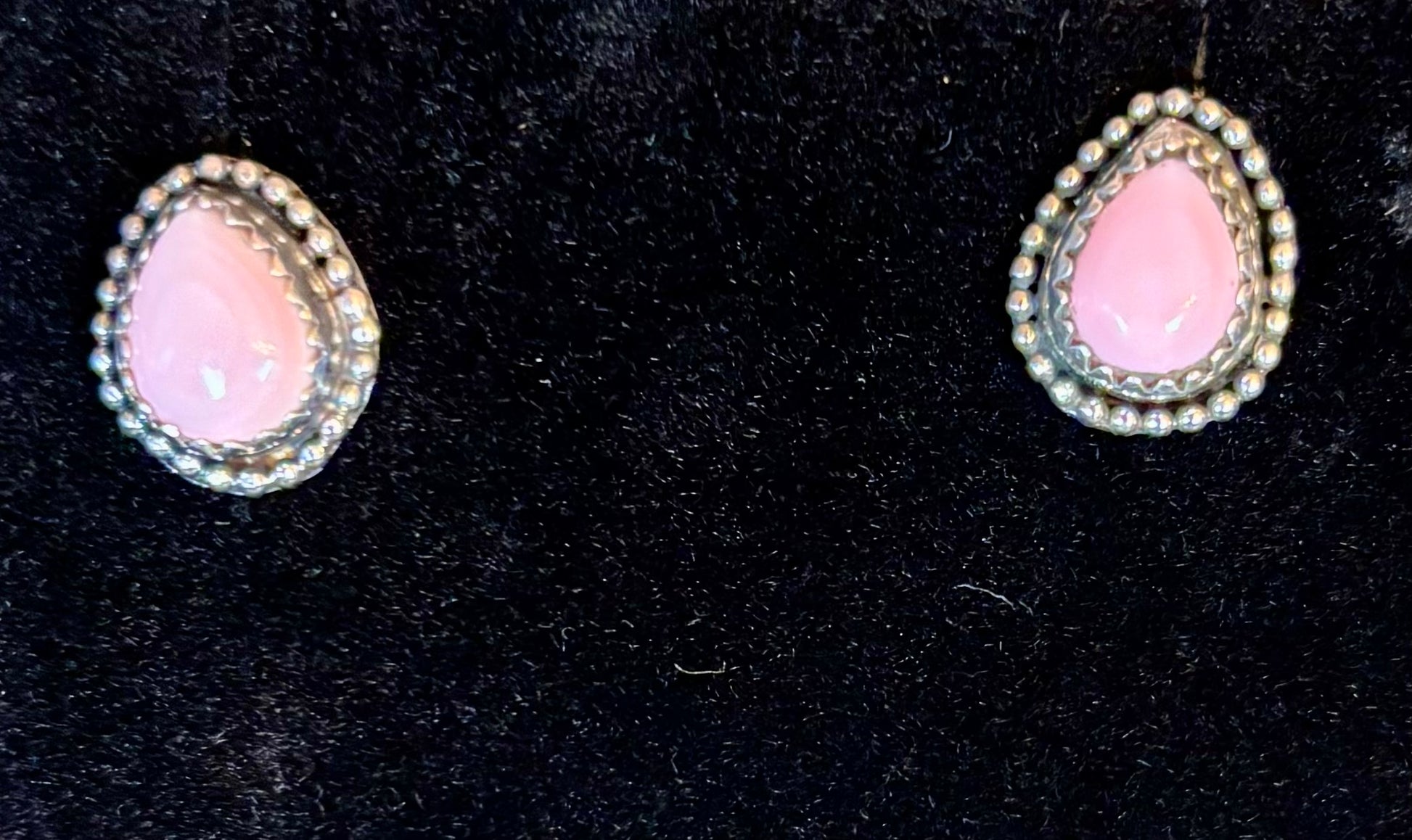 Pair of pink teardrop earrings on a black background