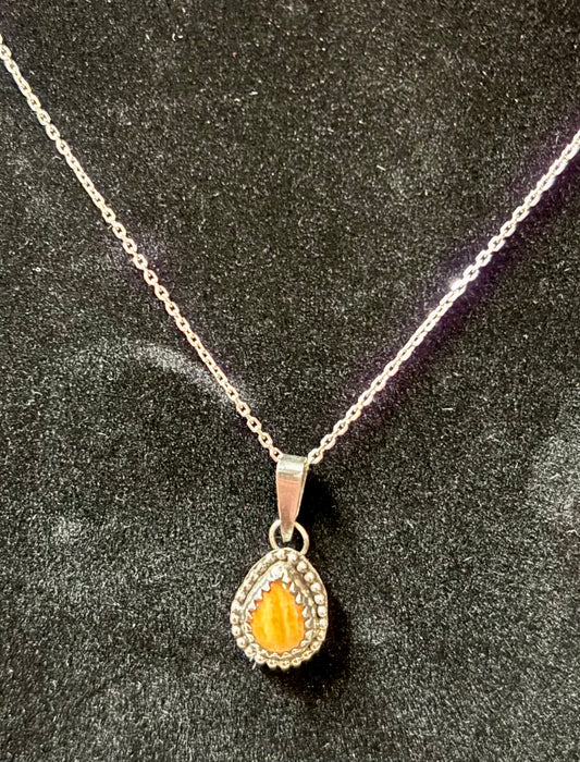 Silver necklace with a teardrop-shaped pendant on a dark textured background