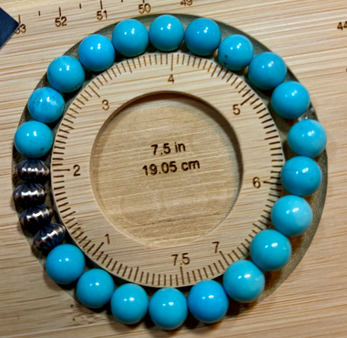 Blue beads on a wooden measuring tool showing measurements.