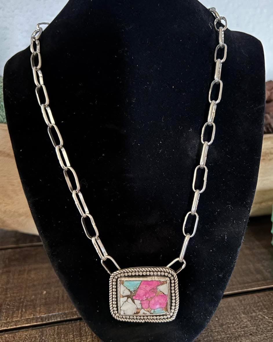 Necklace with a colorful pendant on a black stand