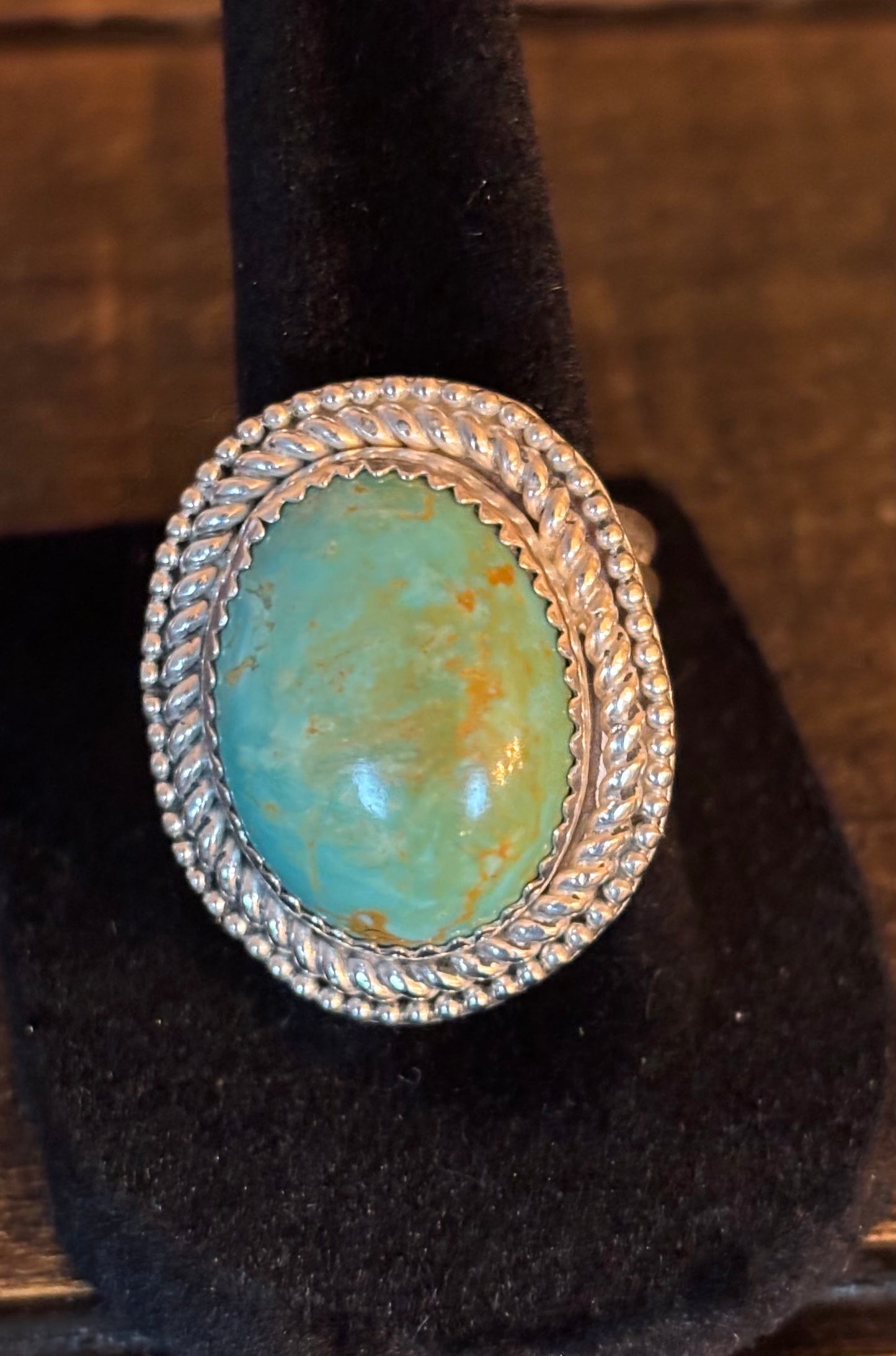 Turquoise ring with silver band on a black stand