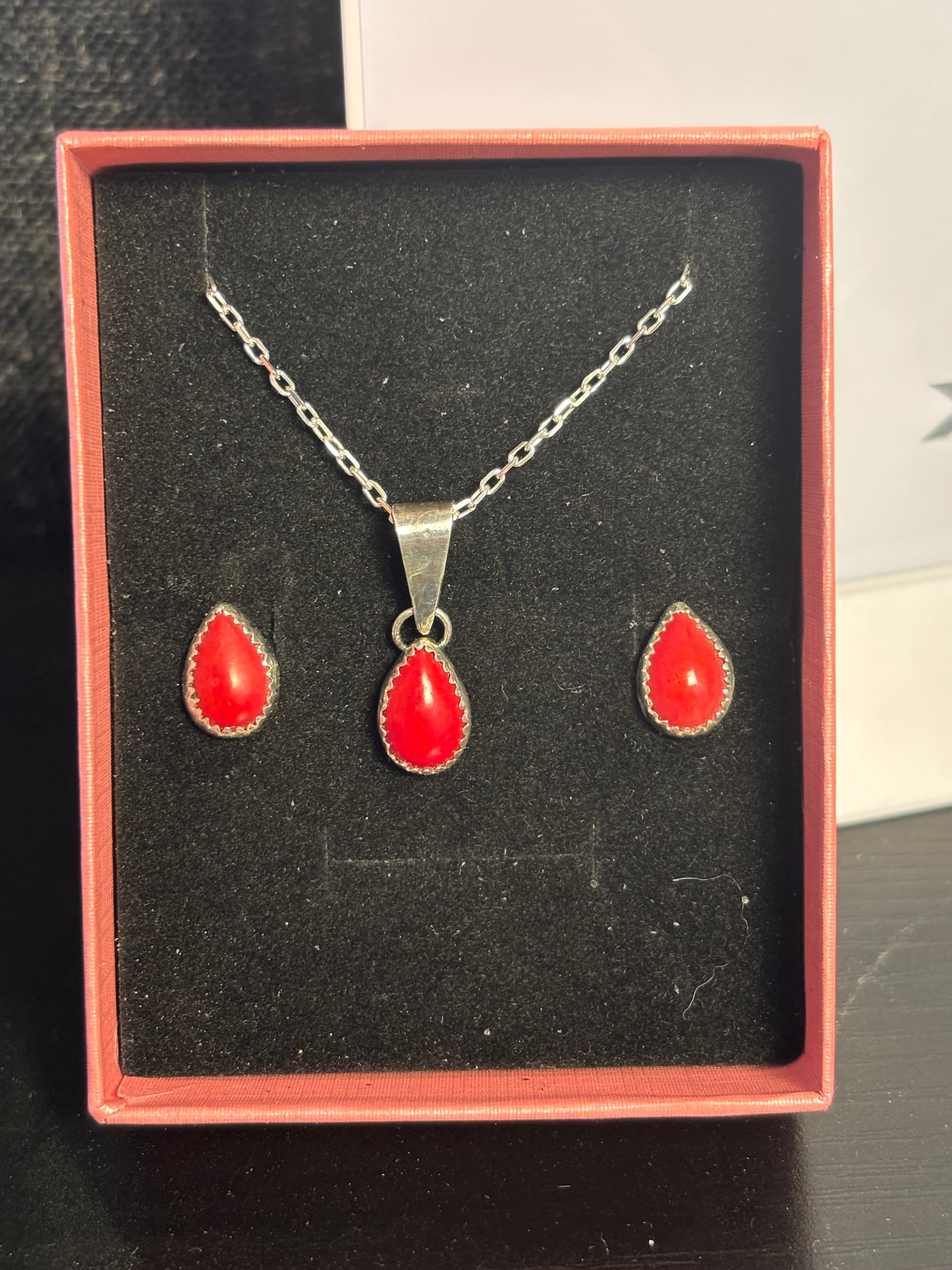 Jewelry set with red stones and silver chains in a box