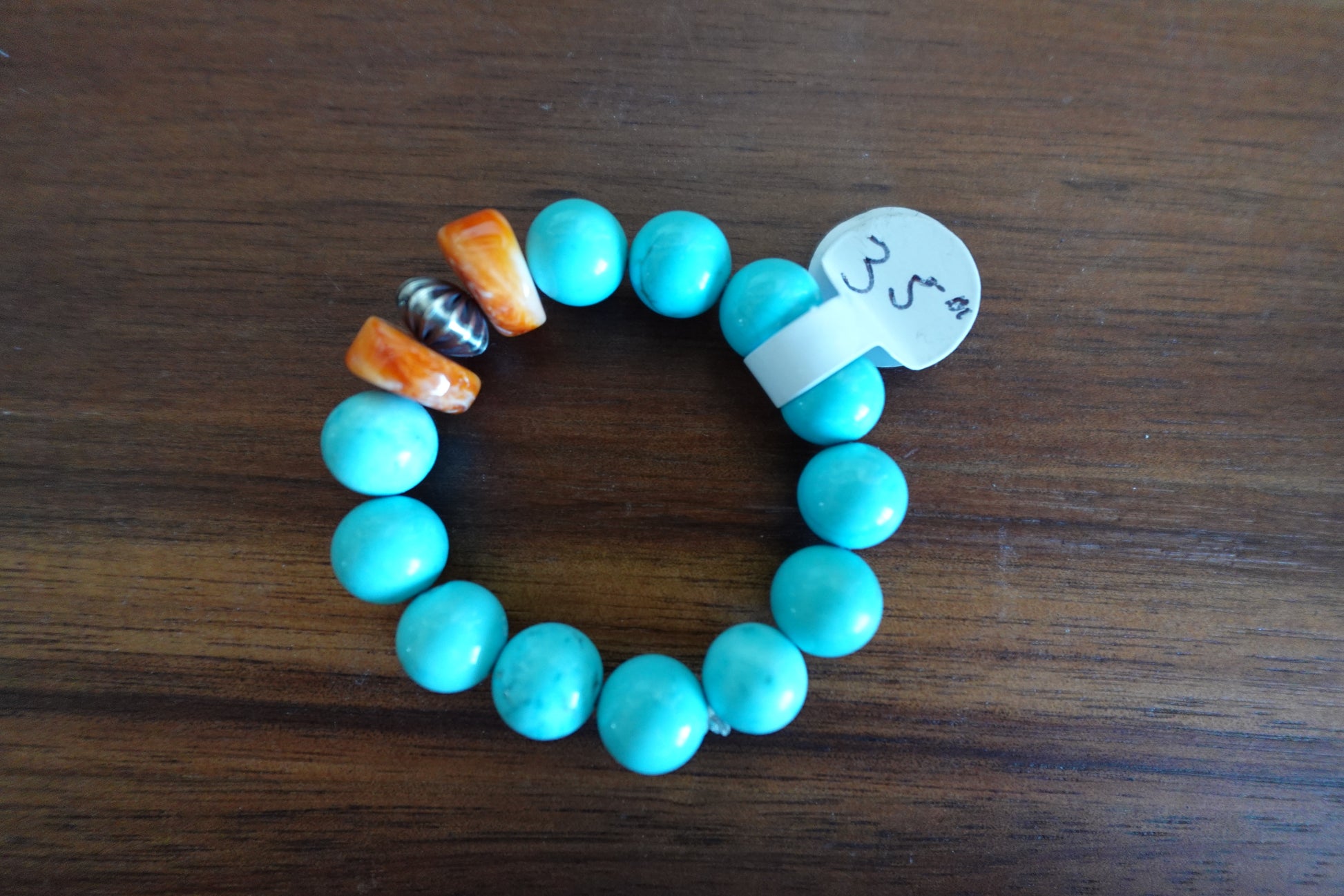 Turquoise beaded bracelet with colorful accents on a wooden surface