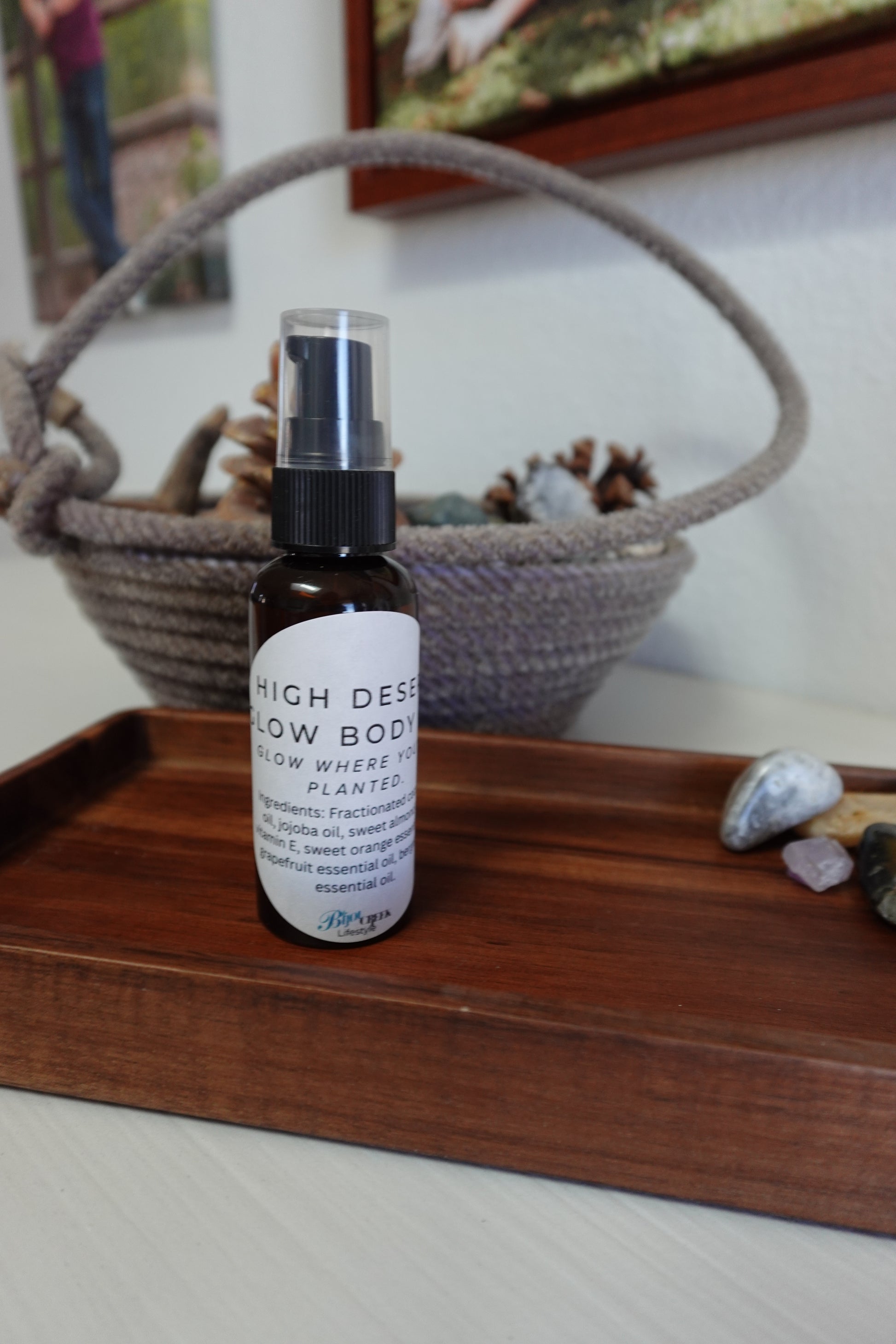 Bottle of body oil on a wooden tray with a rope basket in the background