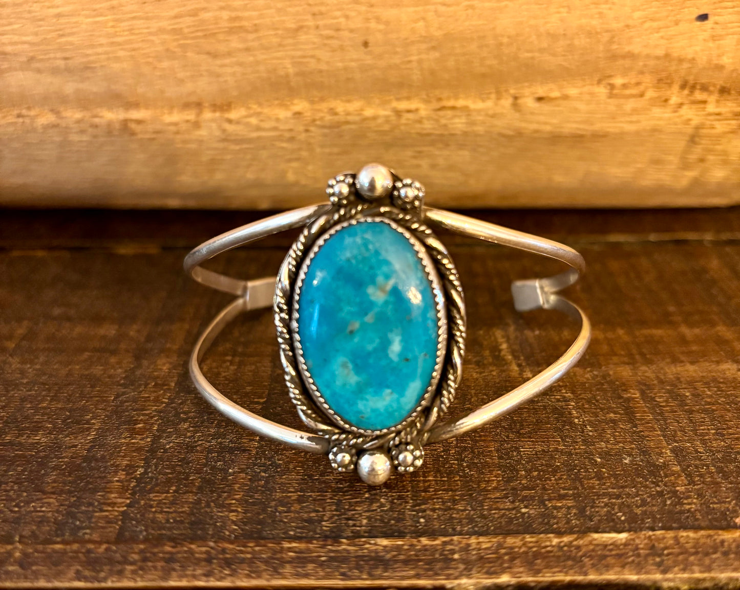 Silver bracelet with a turquoise stone on a wooden surface