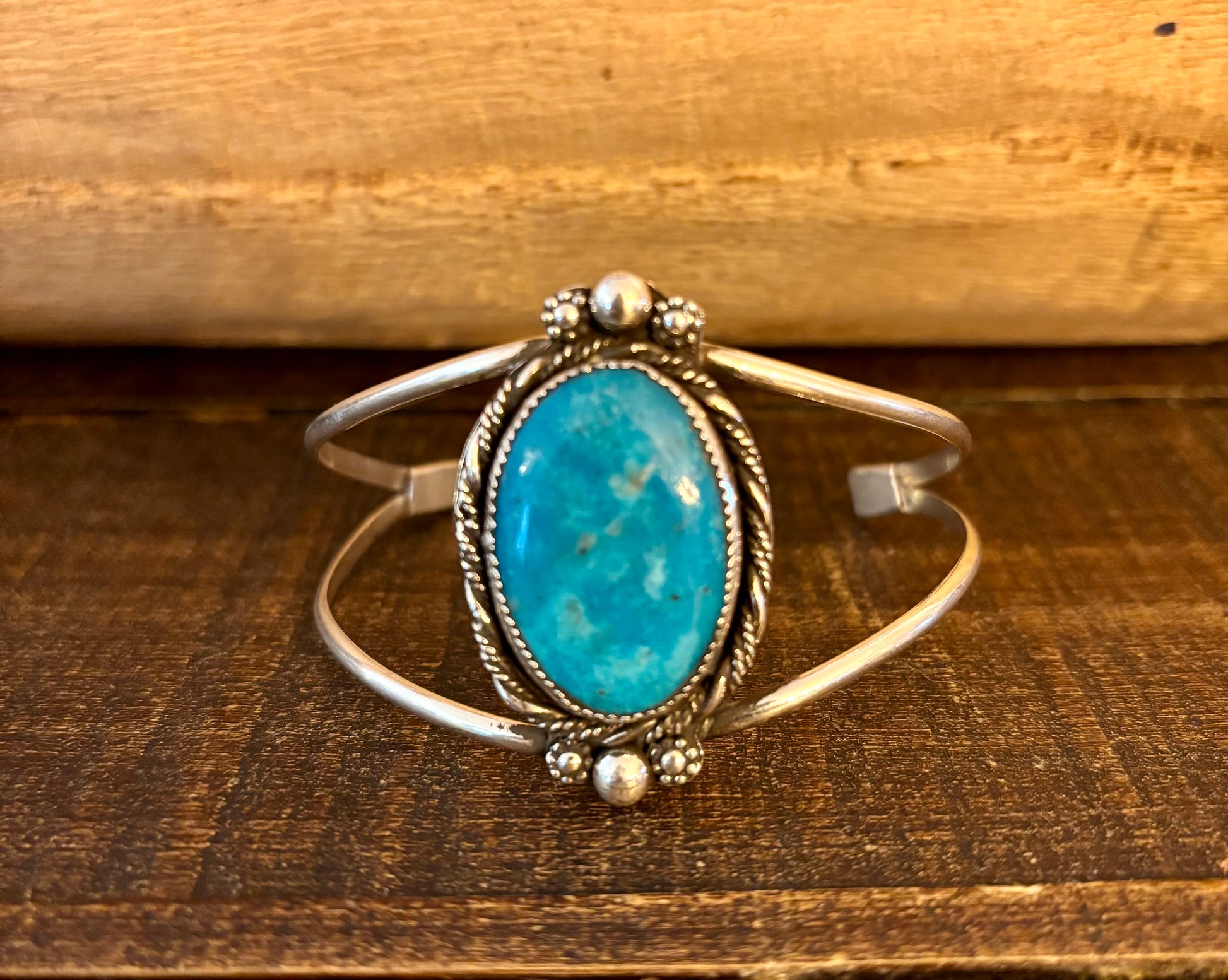Silver bracelet with a turquoise stone on a wooden surface