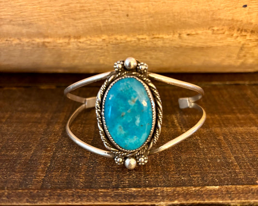 Silver bracelet with a turquoise stone on a wooden surface