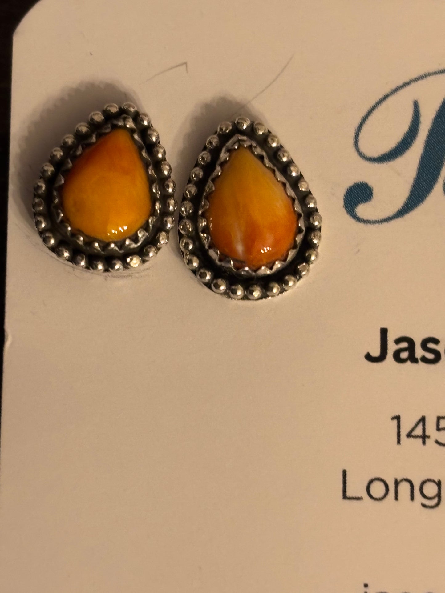 Pair of amber teardrop earrings with silver setting on a card.