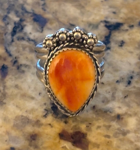 Silver ring with an orange stone on a marble surface