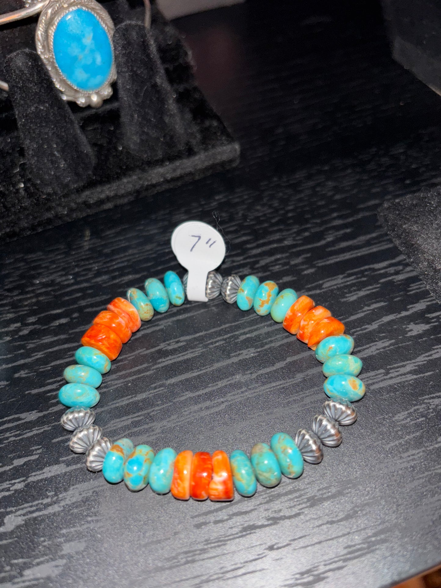 Colorful beaded bracelet with silver clasp on a dark textured surface