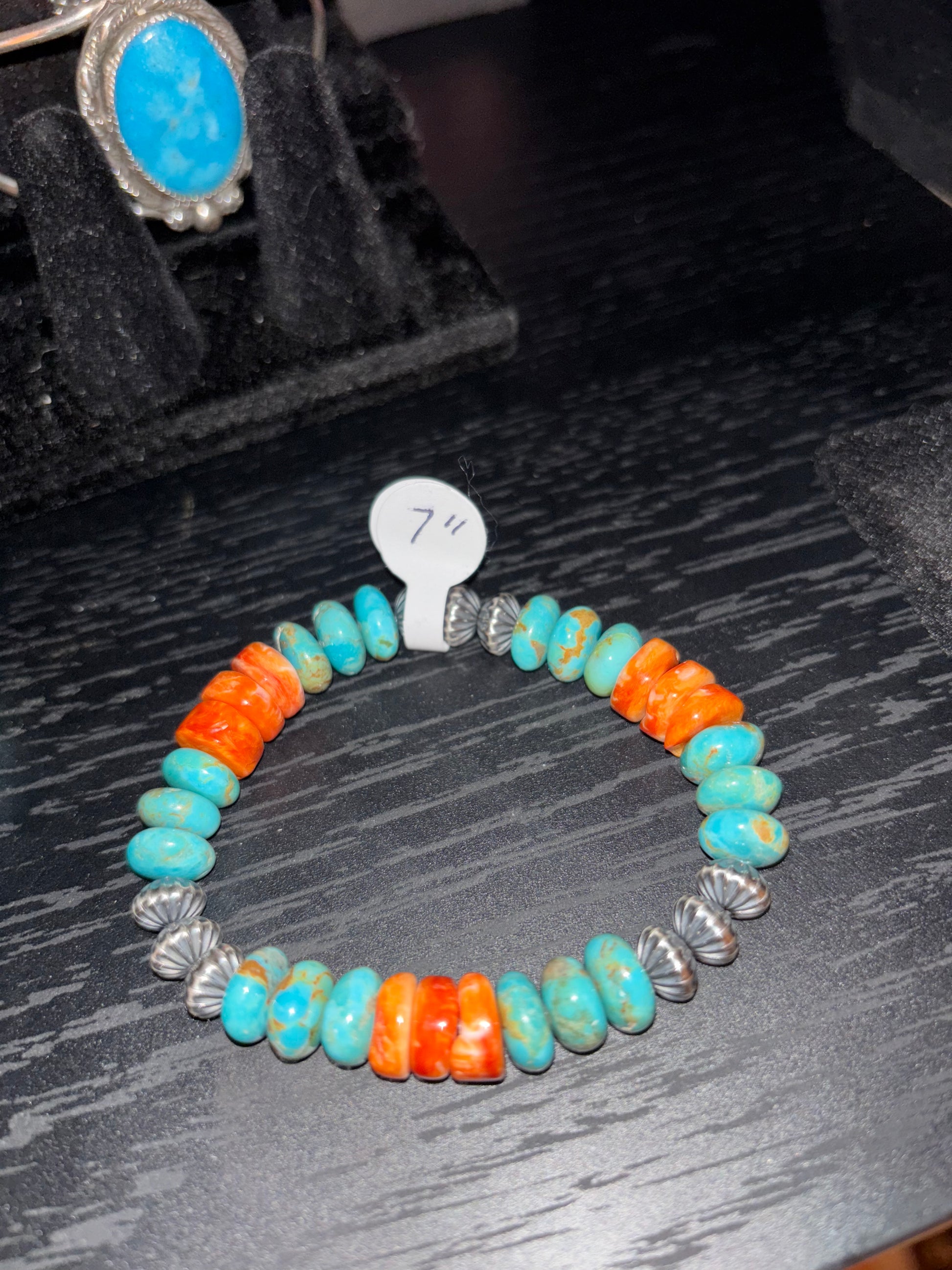 Colorful beaded bracelet with silver clasp on a dark textured surface