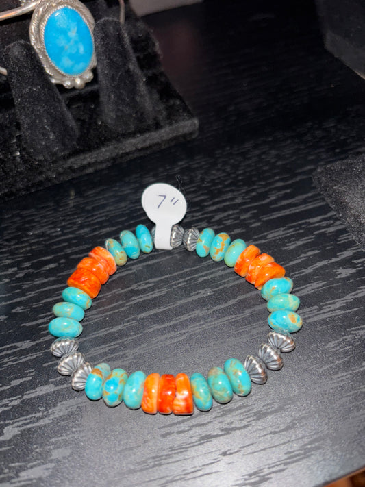 Colorful beaded bracelet with silver clasp on a dark textured surface