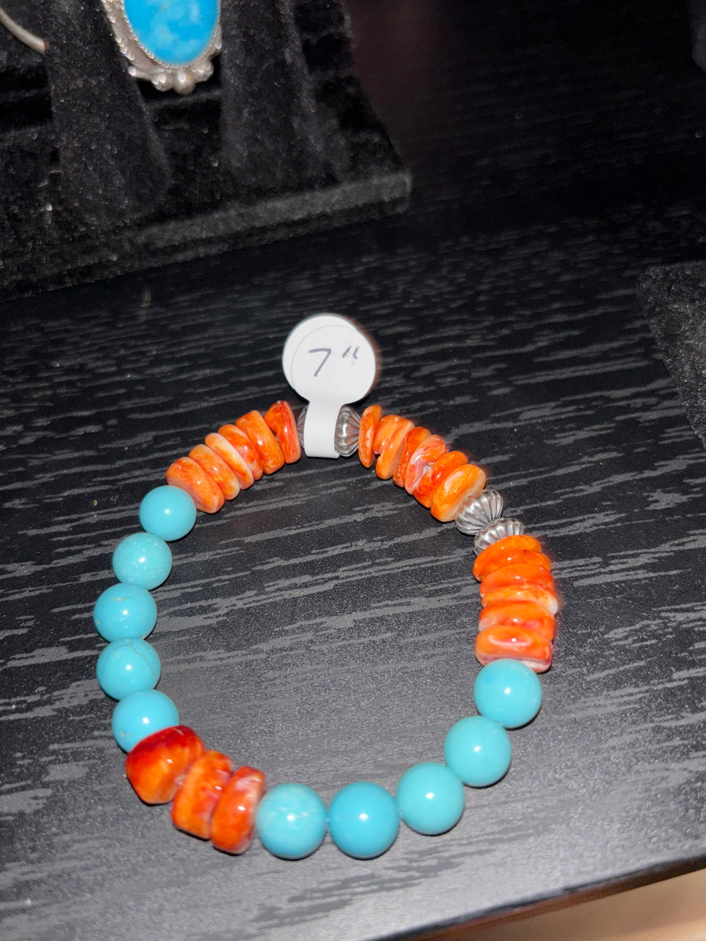 Bracelet with orange and blue beads on a dark textured surface