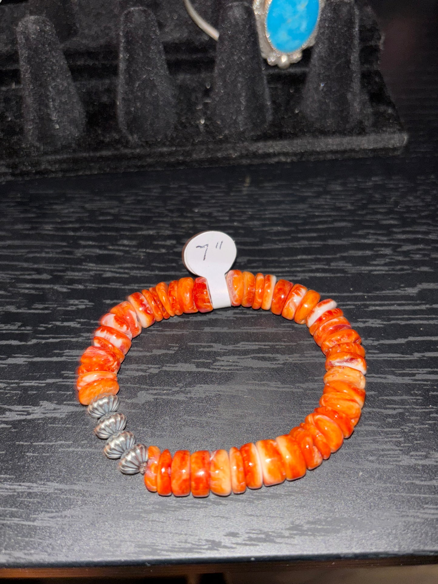 Orange beaded bracelet with silver accents on a dark textured surface