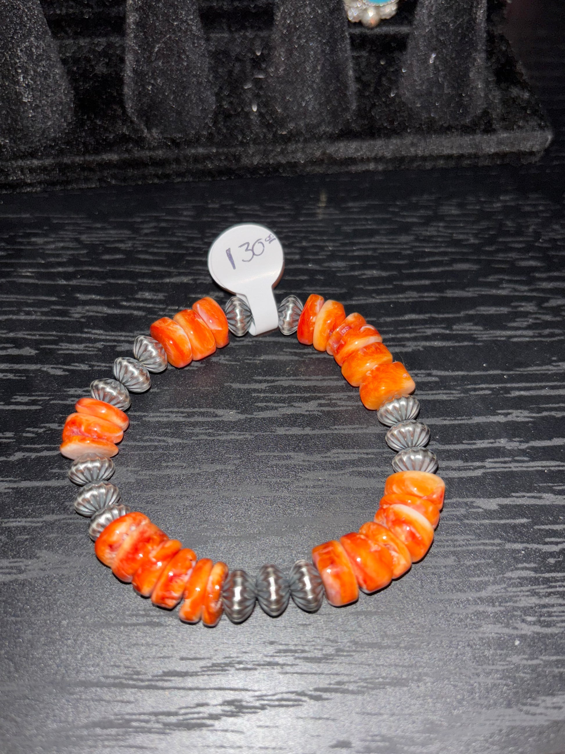 Bracelet with orange and silver beads on a dark textured background