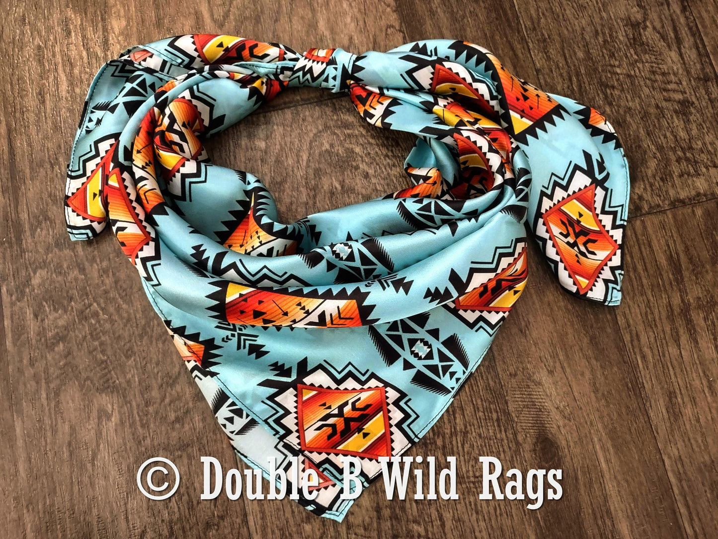 Colorful patterned bandana on a wooden surface with 'Double B Wild Rags' branding.