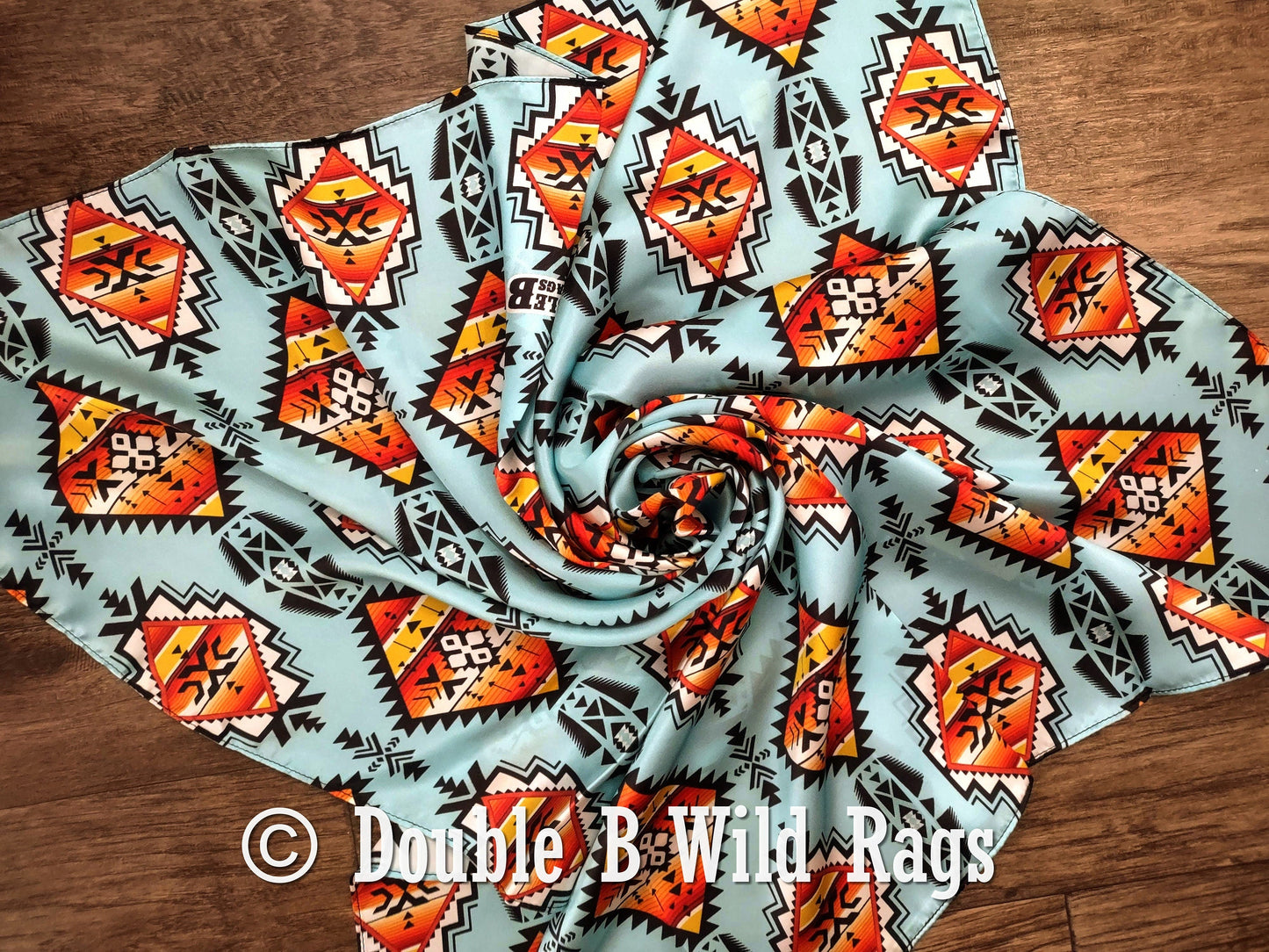 Fabric with geometric pattern on a wooden surface, featuring the brand 'Double B Wild Rags'.