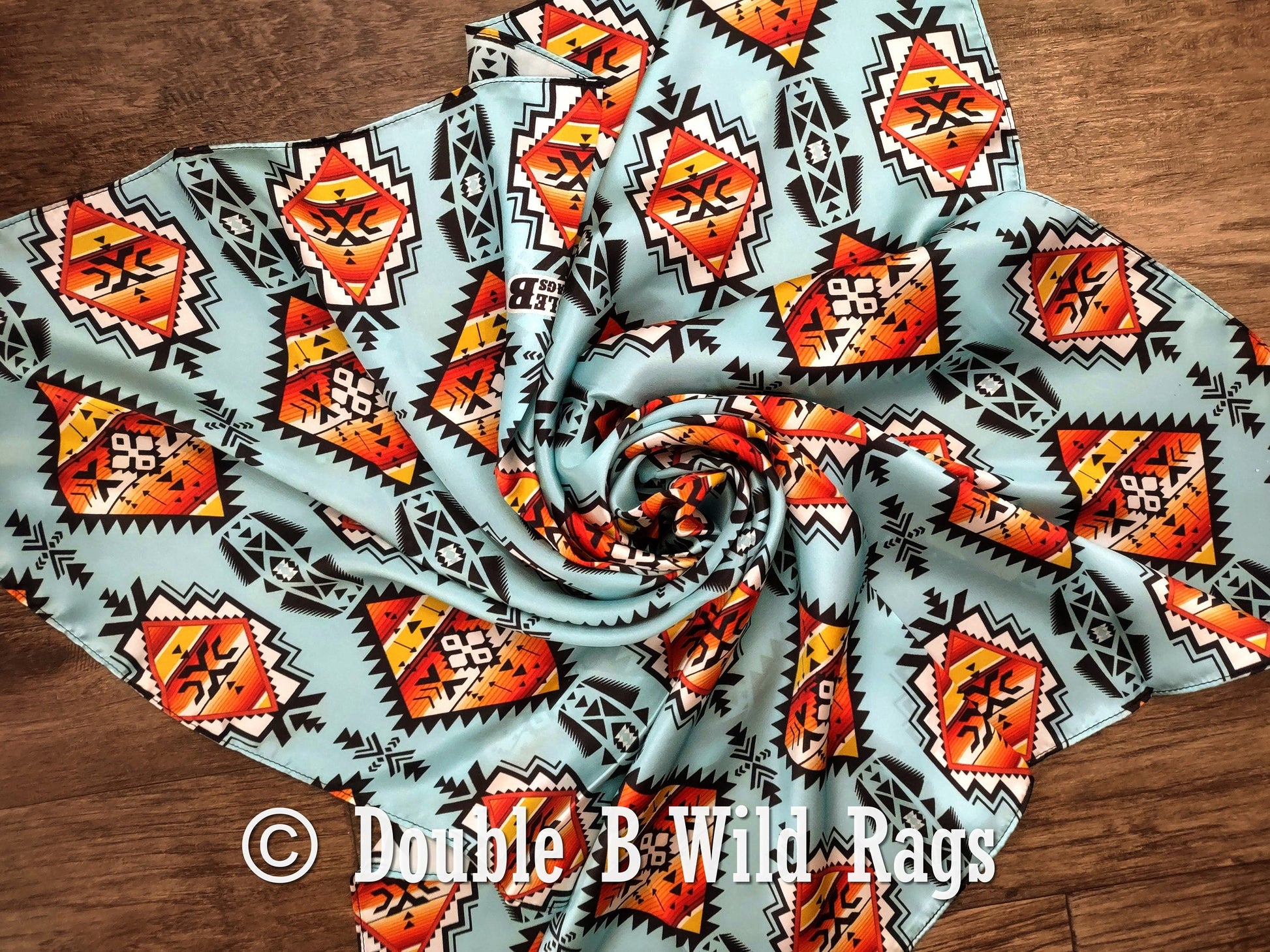 Fabric with geometric pattern on a wooden surface, featuring the brand 'Double B Wild Rags'.