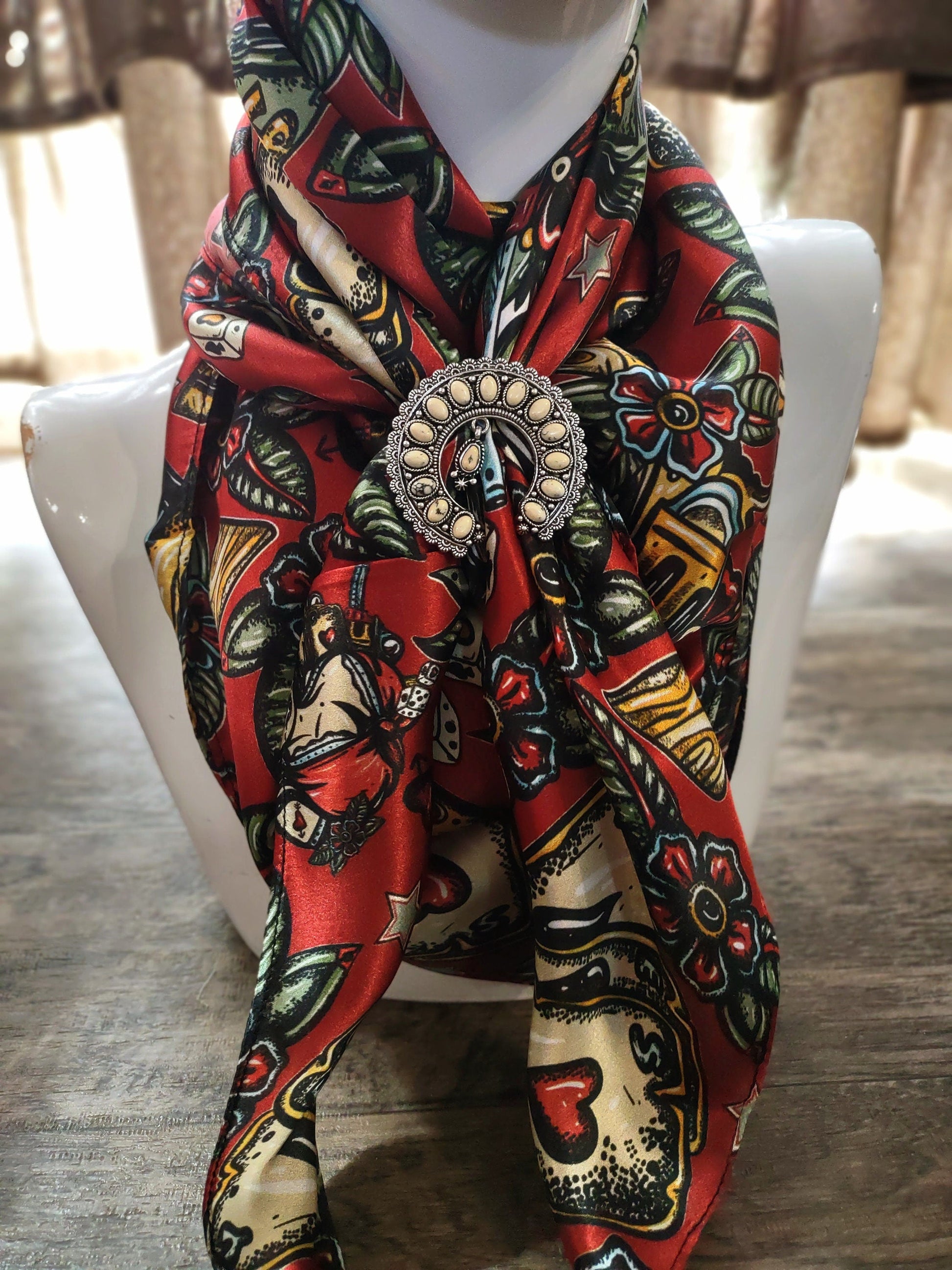 Colorful patterned scarf with a decorative brooch on a mannequin against a neutral background