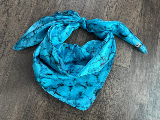Turquoise patterned scarf on a wooden surface
