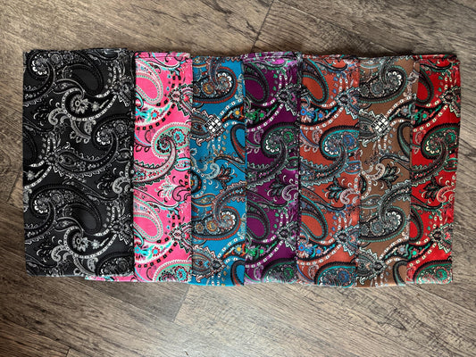 Set of five fabric swatches with paisley patterns on a wooden surface